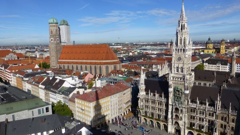 Das Bild zeigt eine Ansicht der Stadt München mit Frauenkirche und Rathaus.