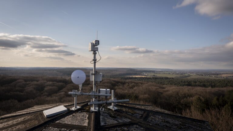 Das Bild zeigt ein Kamerasystem, das in der Ferne ein Waldgebiet überwacht.