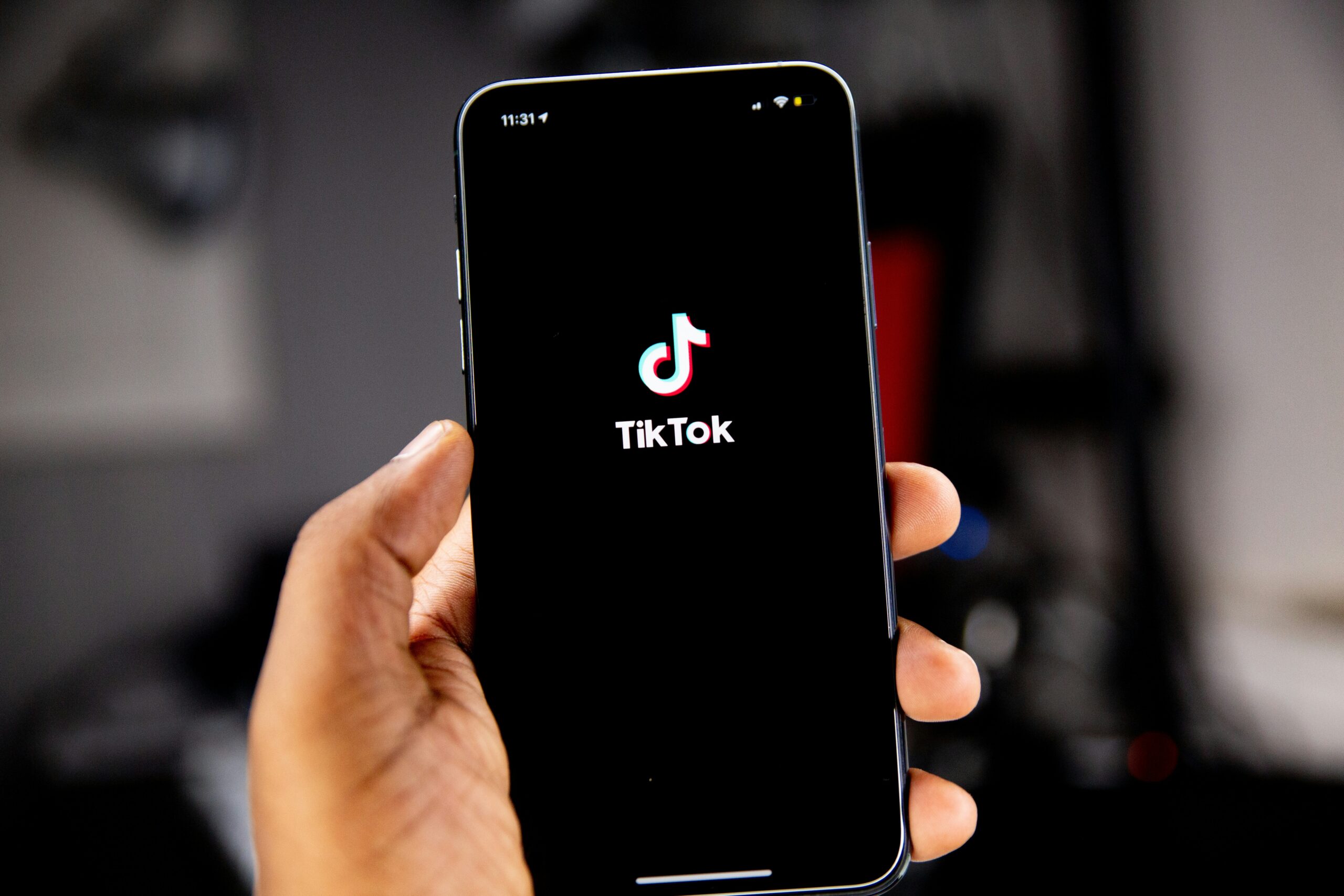 Eine Hand hält ein Smartphone hoch, auf dessen Screen das TikTok-Logo zu sehen ist.