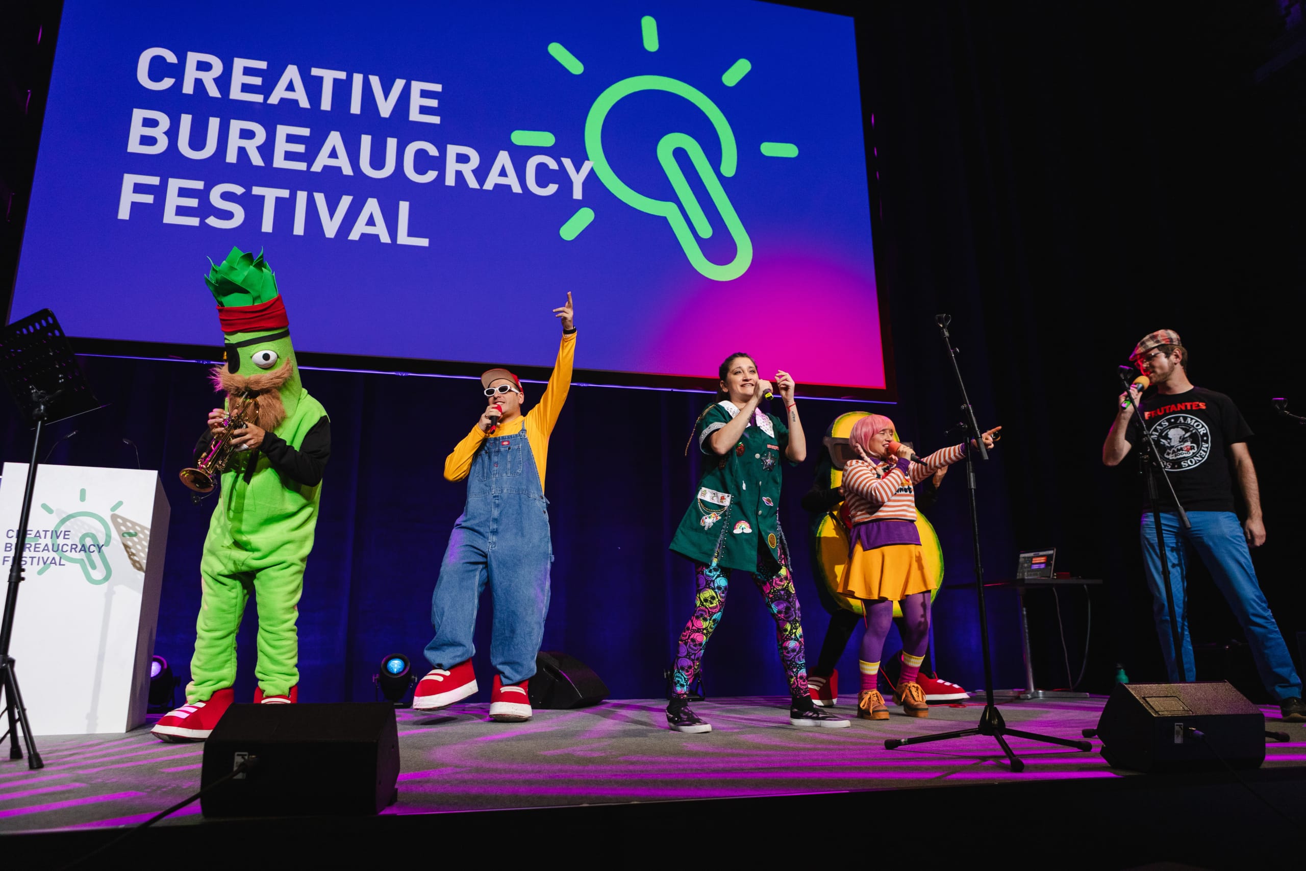 Das Bild zeigt eine Bühne des Creative Bureaucracy Festival auf der kostümierte Menschen Musik machen.