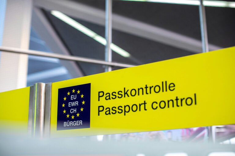 Gelbes Schild mit der aufschrift Passkontrolle/Passport Control