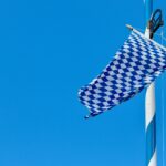 Blau-weißer Stander mit Rautenmuster (Bayernflagge) weht im Wind, im Hintergrund blauer Himmel.