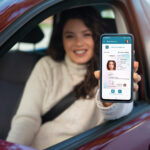 Eine junge Frau hält ihr Smartphone in die Kamera, auf dessen Bildschirm ihr Führerschein zu sehen ist.