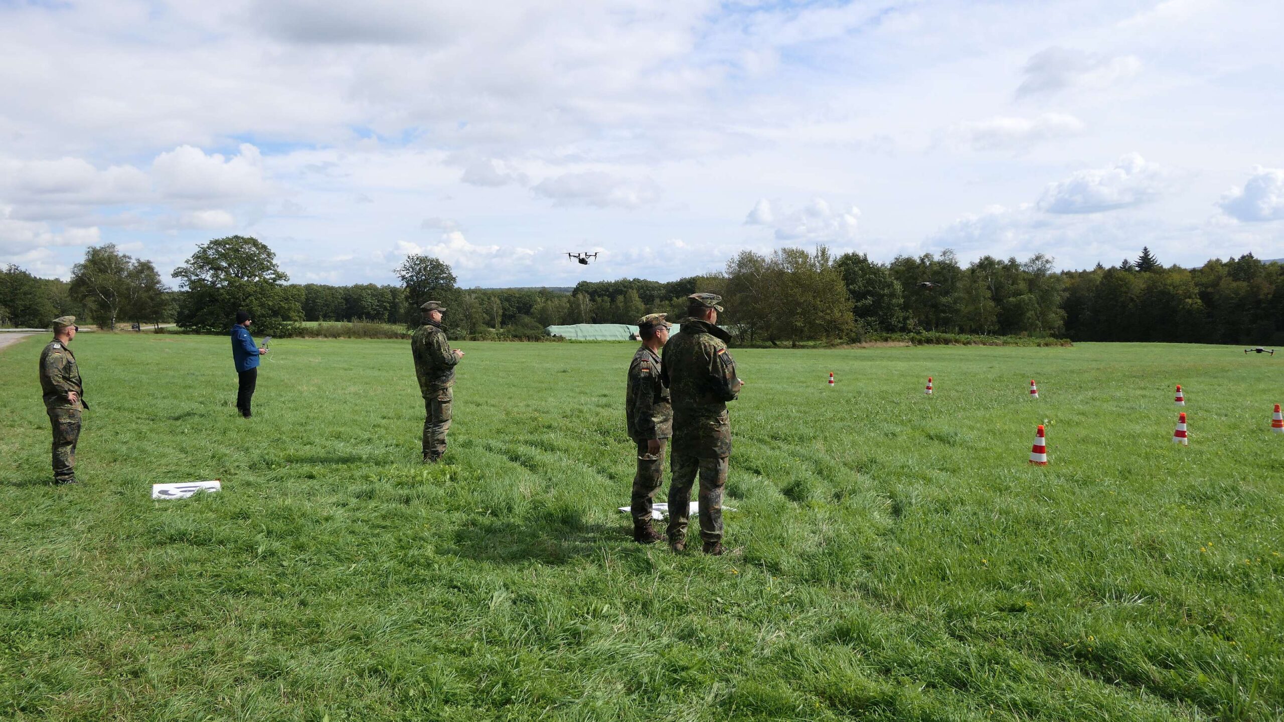 Außenaufnahme: Wiese mit mehreren Männern in Uniform, auf dem Boden eine weiße Markierung.