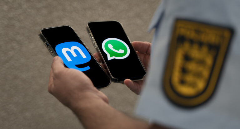 Person, an deren Hemdsärmel die Hohheitszeichen von Baden-Württemberg zu sehen sind, hält zwei Smartphones in den Händen - je eines mit dem Logo von Mastodon und von WhatsApp.