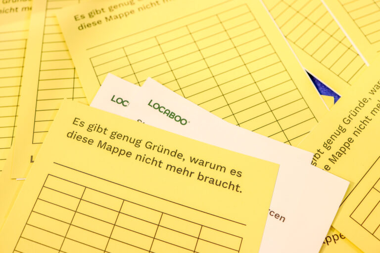 Stapel von typischen gelben Verwaltungsmappen mit der untypischen Aufschrift: Gute Gründe, warum es diese Mappe nicht mehr braucht.