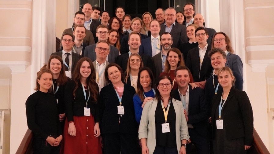 Gruppe von Personen in formeller Kleidung, auf einer Treppe zum Gruppenfoto aufgestellt.