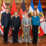 Die Finanzministerinnen und -Minister der Länder Hamurg, Bremen, Niedersachsen und Schleswig-Holstein stehen vor einer Treppe, im Hintergrund sind die jeweiligen Landesfahnen drapiert.