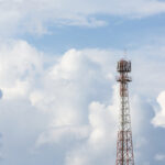 Antennenturm vor blauem Himmel und Wolken.