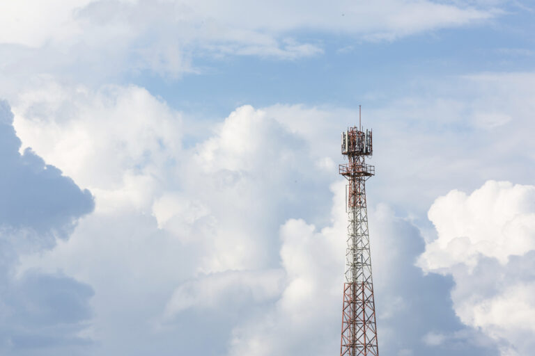 Antennenturm vor blauem Himmel und Wolken.