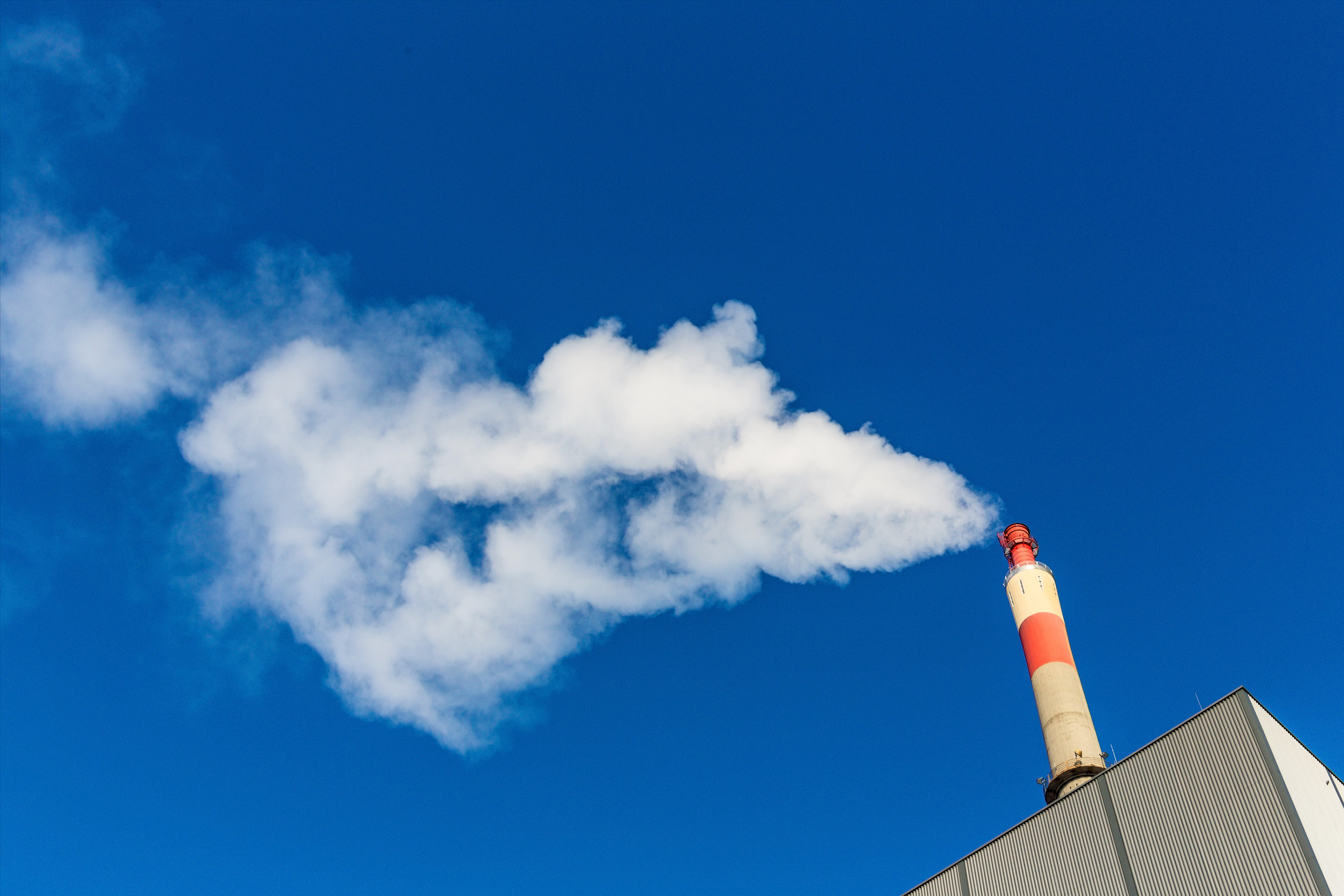 Rauch aus Industrieschornstein vor blauem Himmel