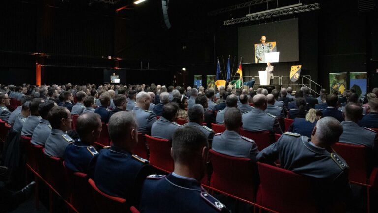 Ein Mann in Uniform hält vor einem großen Publikum an Soldatinnen und Soldaten eine Rede.