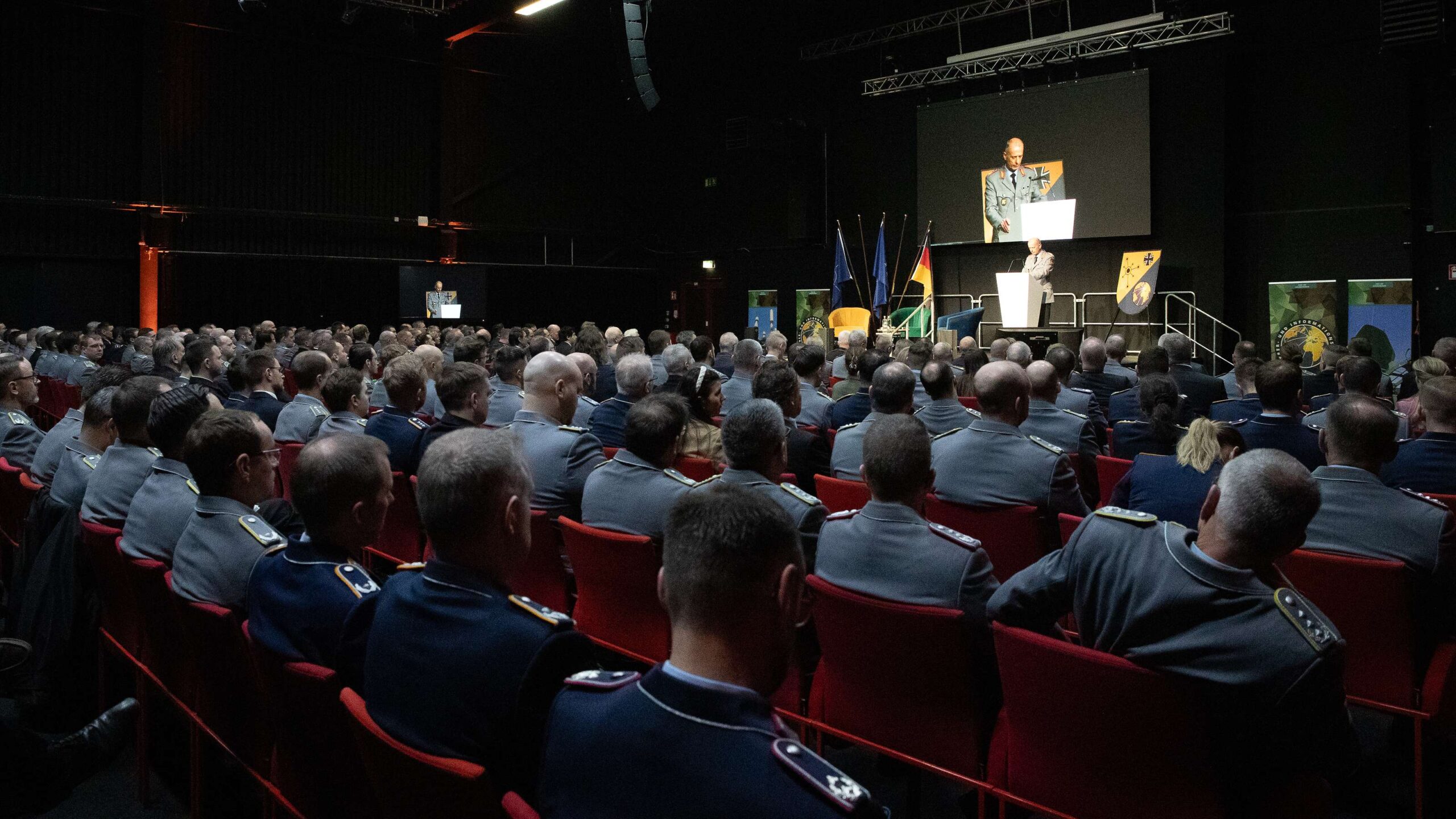 Ein Mann in Uniform hält vor einem großen Publikum an Soldatinnen und Soldaten eine Rede.